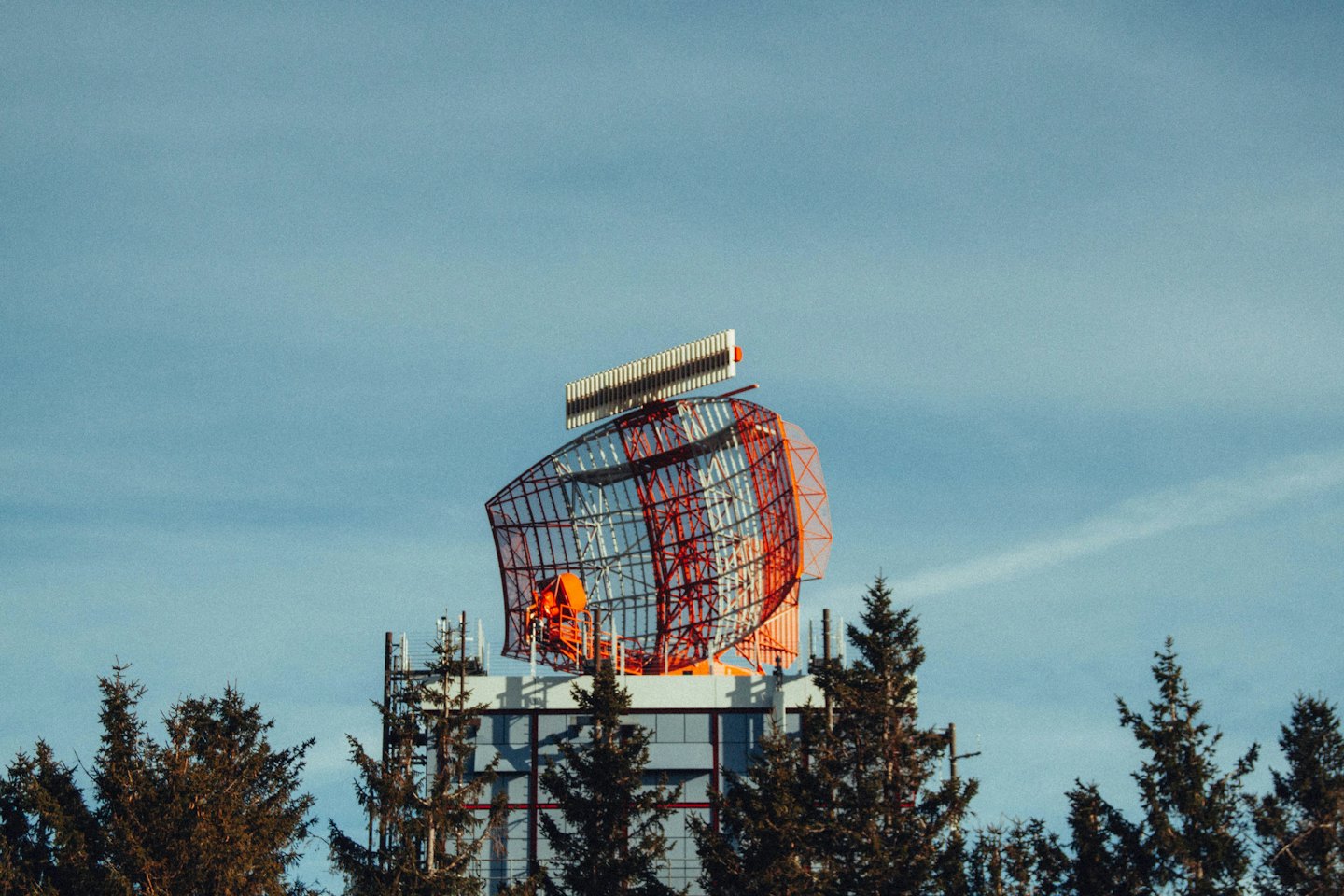 Een grote radarantenne staat bovenop een gebouw.